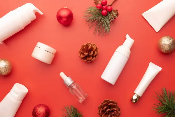 Skincare products with Christmas festive decorations on red background. Christmas sale of beauty products concept.