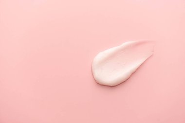 Pembe arka planda cilt kremi lekesi. Yüz kreminin kozmetik losyon dokusu, vücut nemlendiricisi ve saç kremi. Güzellik ve kozmetik ürünleri.