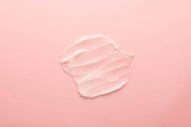 Pembe arka planda cilt kremi lekesi. Yüz kreminin kozmetik losyon dokusu, vücut nemlendiricisi ve saç kremi. Güzellik ve kozmetik ürünleri.