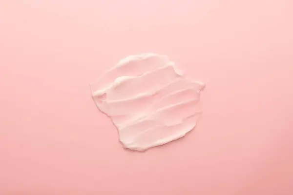 Skincare cream smear on pink background. Cosmetic lotion swatch texture of face cream, body moisturiser and hair conditioner. Beauty and cosmetic product.