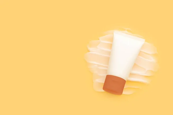 Sunscreen tube with cream texture on yellow background. Plastic bottle of SPF sunblock cream for protect against wrinkles, discoloration and skin cancer. Daily skincare products for sun protection.