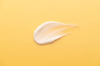 Sarı arka planda cilt kremi lekesi. Güneş kreminin kozmetik losyon dokusu, yüz kremi, vücut nemlendirici ve saç kremi. Güzellik ve kozmetik ürünleri.