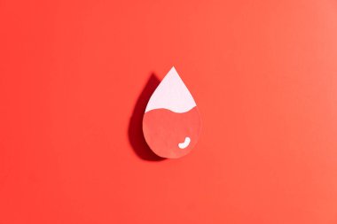 Düşük kan seviyeli kan damlası kırmızı arka planda kağıttan yapılmış. Anemi, orak hücre hastalığı, hemofili, lösemi ve ITP gibi hematolojik bozukluklar kavramı.