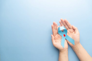 Dünya Diyabet Günü Farkındalık Konsepti. Ellerinde diyabet için kan damlası sembolü olan mavi kurdele var. Diyabetle mücadeleye destek.