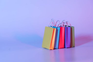 Neon arka planda renkli kağıt alışveriş torbaları. Çevrimiçi alışveriş için yaratıcı fikir, yaz indirimi, süpermarket, indirimli promosyon ve Kara Cuma konsepti.