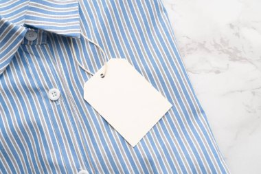 Mermer zemin üzerinde boş etiket etiketi olan mavi çizgili gömlek. Tasarım için hazırlan.