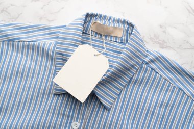 Mermer zemin üzerinde boş etiket etiketi olan mavi çizgili gömlek. Tasarım için hazırlan.