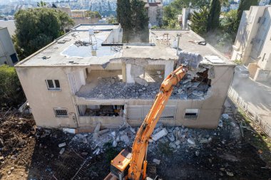 Bir evin sökülmesi. Kazıcı yeni bir inşaat projesi için barakaları yıkıyor. 