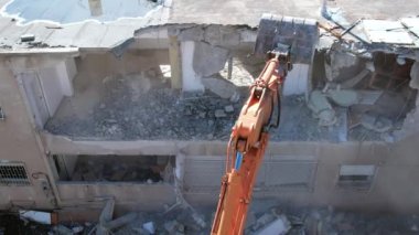 Bir evin sökülmesi. Kazıcı yeni bir inşaat projesi için barakaları yıkıyor. 