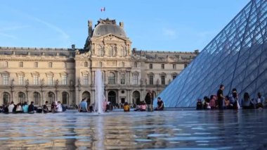 Louvre Museum, Pyramids, fountain. Tourists walk on the square of the Louver Museum. 