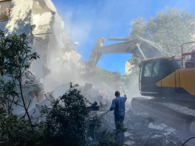 Bir evin sökülmesi. Kazıcı yeni bir inşaat projesi için barakaları yıkıyor. 
