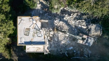 Bir evin sökülmesi. Kazıcı yeni bir inşaat projesi için barakaları yıkıyor. 