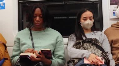 Metroda farklı etnik kökenlere sahip insanlar yan yana oturur..