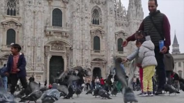  Milano Duomo Katedrali 'nin önündeki meydanda güvercinleri besleyen turistler.