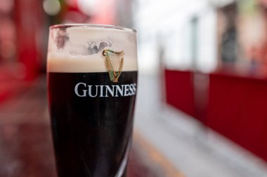 Bir bardak Guinness birası bir masanın üzerinde duruyor. Derin ve zengin bir renk yayıyor.. 