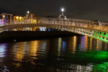 Dublin şehir merkezindeki Liffey Nehri üzerindeki ünlü yaya Penny Hapenny Köprüsü gece görüşü.