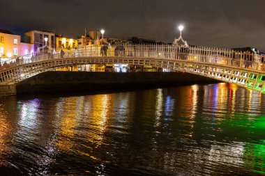 Night view of the iconic pedestrian Penny Hapenny Bridge over the River Liffey in downtown Dublin. clipart