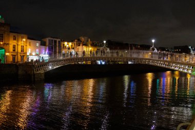 Dublin şehir merkezindeki Liffey Nehri üzerindeki ünlü yaya Penny Hapenny Köprüsü gece görüşü.