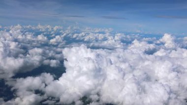 Uçsuz bucaksız yeşil manzaraların üzerinde yüzen tüylü beyaz bulutların çarpıcı manzarası.