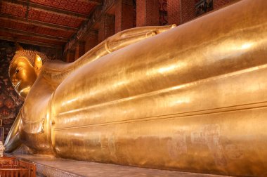 Buda tılsımı Buda 'yı yaslanmış bir şekilde gösterir. Majestelerinin ayakları eşit bir şekilde örtüşüyor ve sol eli Tayland 'da vücudunu çaprazlıyor.. 