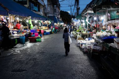 Pazar hareketli satıcılar ve parlak ışıklarla aydınlatılmış renkli vitrinlerle dolup taşıyor..