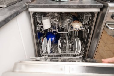 Kadın ev işi için bulaşık makinesi kullanıyor.