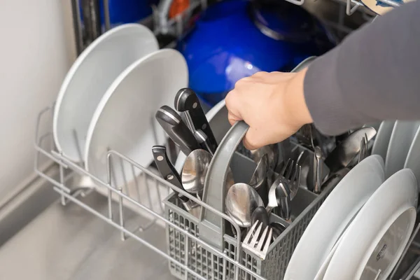 Woman with full dishwasher machine for housework  in kitchen