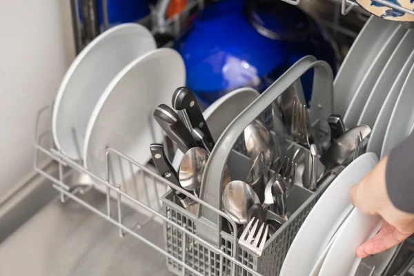 Woman with full dishwasher machine for housework  in kitchen