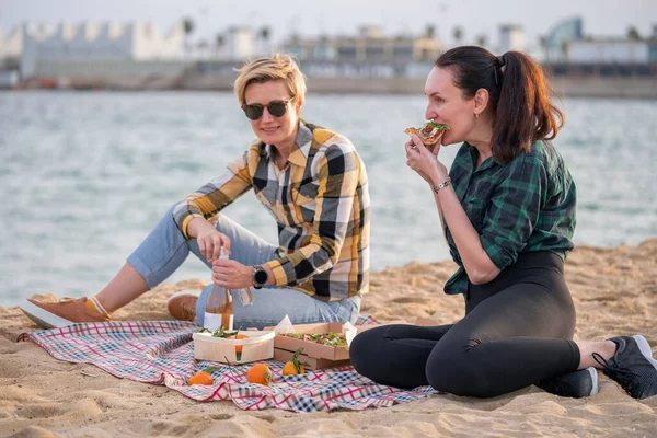 Two Women Beach Picnic White Wine Pizza Friends Hanging Out lizenzfreie Stockfotos