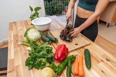 Mutfakta taze sebzelerle, vejetaryen ya da vejetaryen kadınlarla yemek pişiren atletik bir kız. Uygun beslenme kavramı