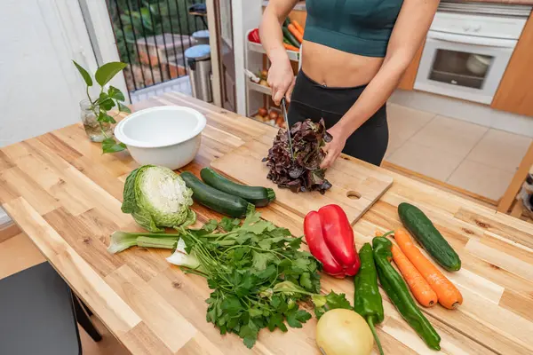 Mutfakta taze sebzelerle, vejetaryen ya da vejetaryen kadınlarla yemek pişiren atletik bir kız. Uygun beslenme kavramı