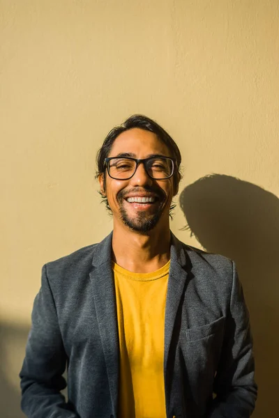 stock image Vertical image of a happy Latin businessman wearing a suit, glasses and standing on a yellow background.