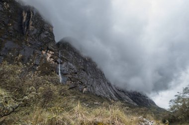 Bulutlarla kaplanmış peyzaj dağında çarpıcı bir şelale var. Stok resim koleksiyonunuza resim gibi bir ekleme
