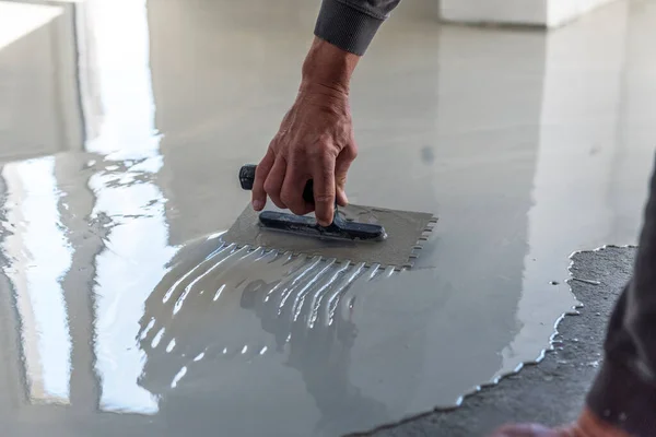建設作業員は 自己平準化エポキシを使用して床を塗装しています セルフレベリングエポキシ セメント床の混合物との平準化 ストック写真