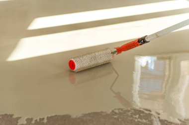 Zemini dümdüz etmek için iğne silindiri. Yerleri çimento karışımıyla döşemek..