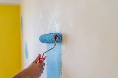 Dekoratörün el boyası silindirle duvarı.