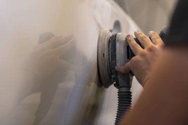 Araba tamirhanesinde araba cilalayan bir adamın elinde öğütücü..