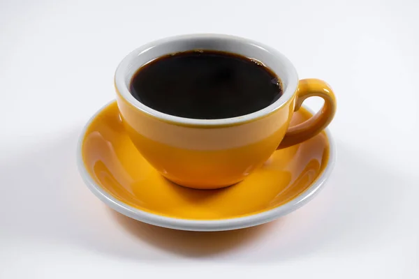 Kafedeki sarı seramik bardakta taze kafein içeceği.