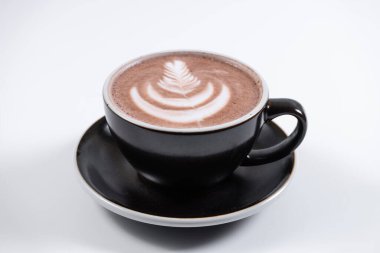 Porselen bardakta köpüklü çikolata içeceği ve kafede çay tabağı.