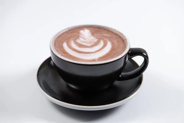 Porselen bardakta köpüklü çikolata içeceği ve kafede çay tabağı.