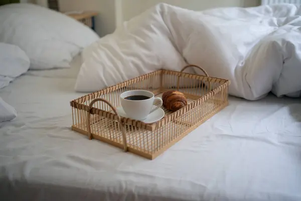 Yatak odasındaki ya da otel odasındaki battaniyenin yanındaki yatak örtüsünün üzerinde içecek ve taze hamur işi.