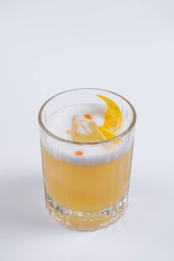 Köpüklü viski kokteyli ve kuru portakal kabuğuyla süslenmiş buz küpü. Beyaz arka planda taze alkollü içeceğe yakın plan. Viski, viski, limon suyu ve şekerle iç.