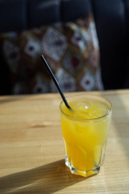 Restorandaki ahşap masada portakal suyunu buzla ve kamışla tazelemek. Kafedeki soğuk içeceğe yakın çekim. Meyveli limonata.