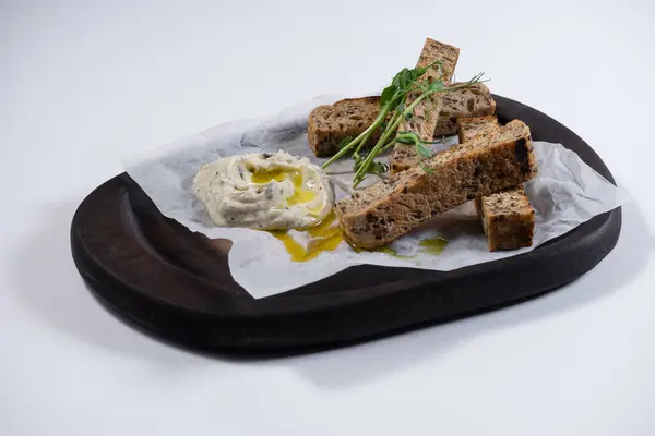 Çavdar ekmeği ve taze tereyağlı çıtır ekmeklere yakın çekim. Beyaz arka planda ahşap tabakta sarımsak soslu tost ekmeği. Kafede bir şeyler atıştır.