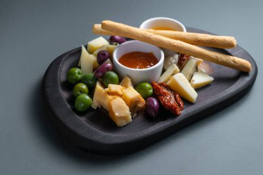 Grissini, zeytin, sos ve balla kaplanmış peynir tabağı. Restoranda peynirli, gouda peynirli ve Edam peynirli Antipasti tabağı