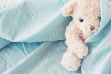 Cute little teddy bear sleeping on a green blanket.