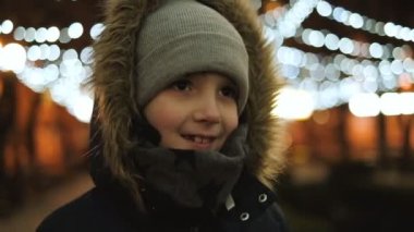 Noel arifesinde akşam sokakta yürüyen bir çocuk. Noel ve Yeni Yıl 'dan Önce Şenlikli Sokak Işığı.