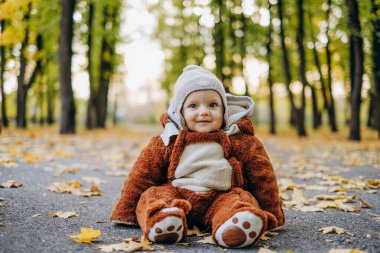 The kid sits in yellow leaves in the park for a walk. Family autumn walk in the evening in the park with children. Happy motherhood.