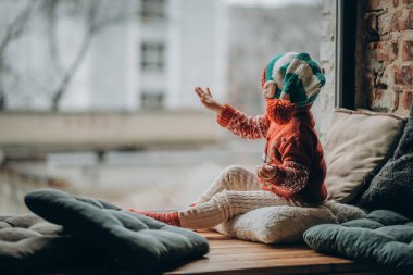 Çocuk pencerede oturur ve Noel Baba 'yı bekler. Noel tatilini bekliyorum. Mutlu bir çocukluk. İtfaiyecileri bekliyoruz..