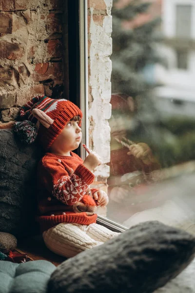 stock image The kid sits at the window and waits for Santa Claus. Waiting for the Christmas holidays. Happy childhood. Waiting for firefighters.